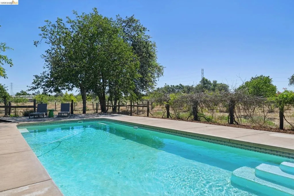 Rectangular inground pool with integrated steps, surrounded by concrete decking