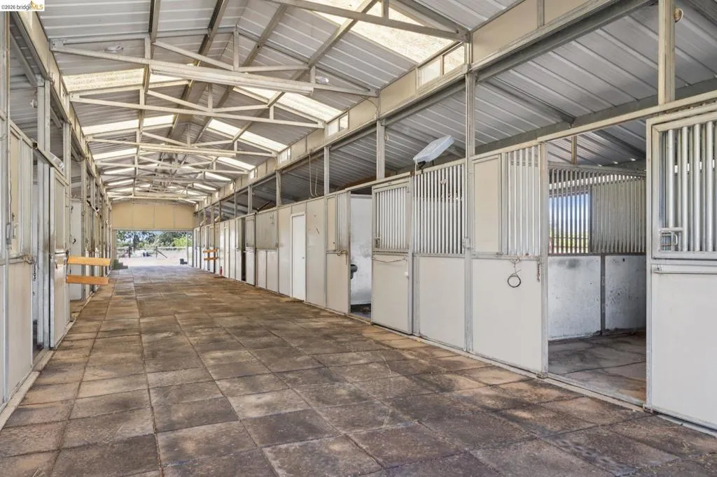 Sturdy metal barn structure featuring multiple stalls with metal gates