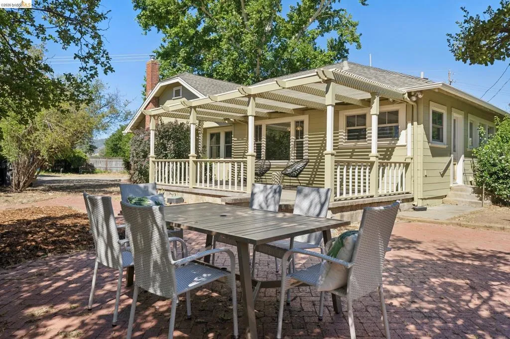 Inviting exterior featuring a shaded front porch with a lattice pergola