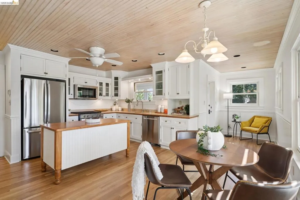 Kitchen featuring wood-finish flooring, white cabinetry, stainless steel appliances, a center island with a wood countertop, and a wood-paneled ceiling