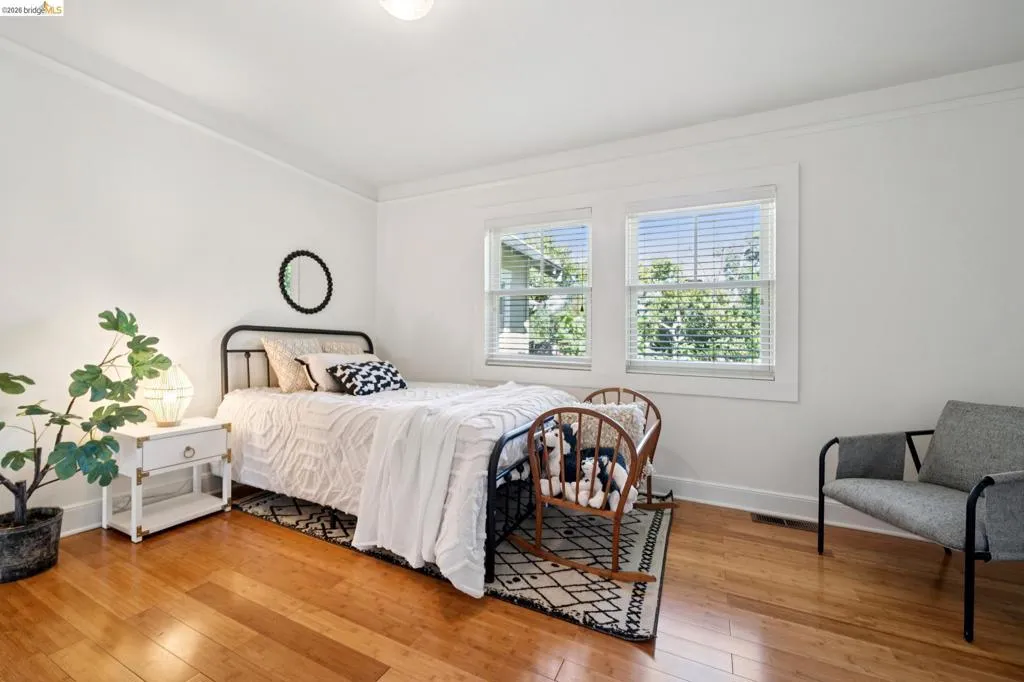 Bright room featuring hardwood flooring, white walls, two windows with blinds, and white trim