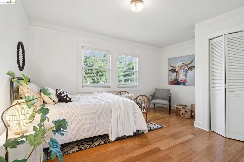 Bright room with wood-finish flooring, two windows with blinds, crown molding, and a flush-mount ceiling light