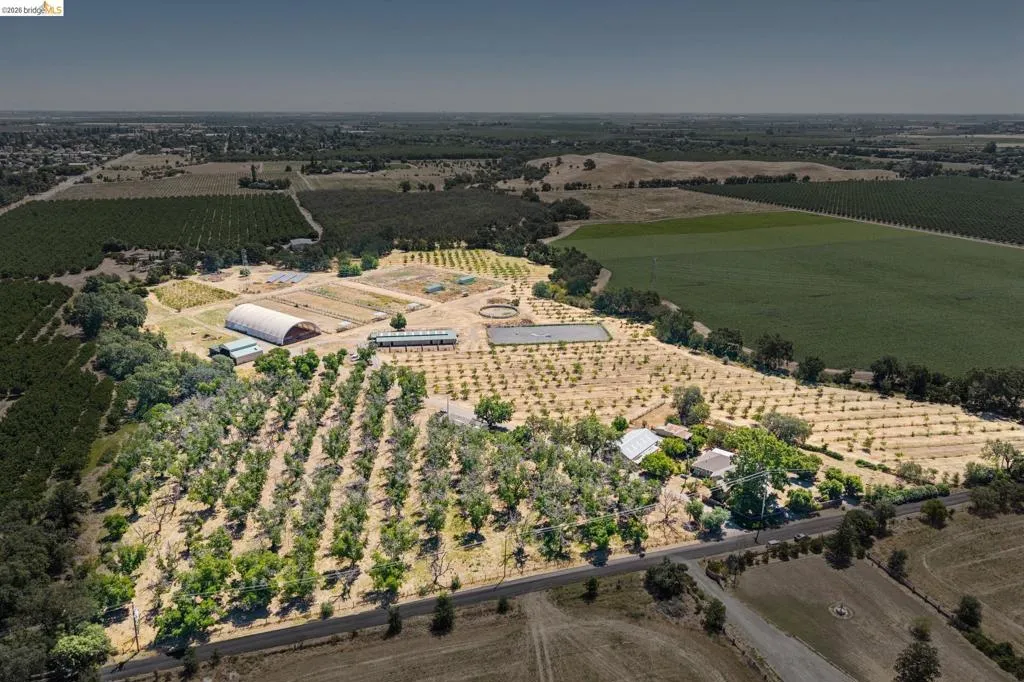 Expansive agricultural property featuring multiple cultivated fields, an arched Quonset hut, and various outbuildings