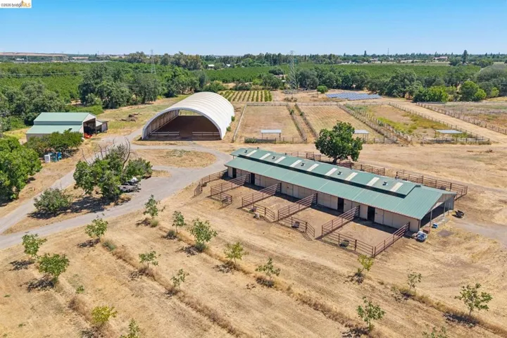Equestrian facility featuring a covered arena, a multi-stall barn with individual paddocks, and multiple fenced turnout areas