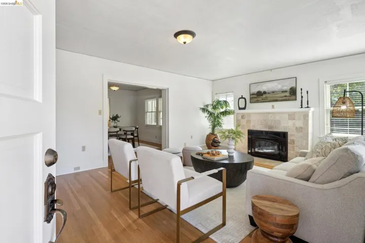 Living room featuring wood-finish flooring, a tiled fireplace with a black insert, white walls, and a ceiling light fixture