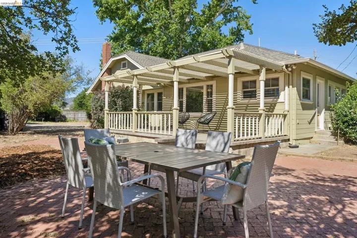 Inviting exterior featuring a shaded front porch with a lattice pergola
