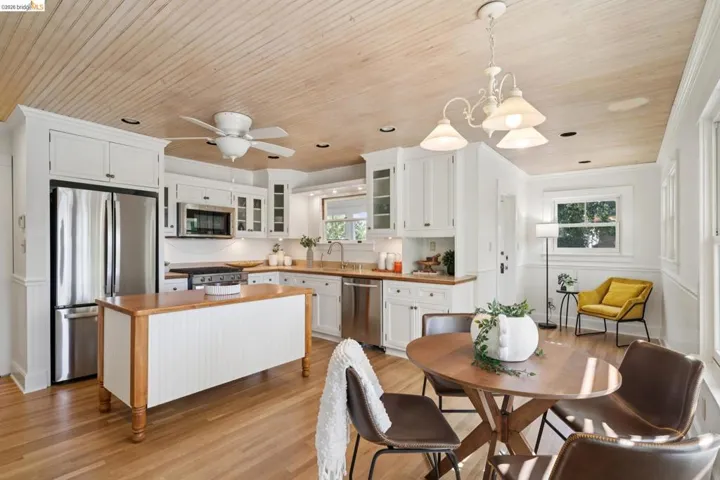 Kitchen featuring wood-finish flooring, white cabinetry, stainless steel appliances, a center island with a wood countertop, and a wood-paneled ceiling