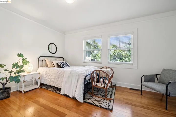 Bright room featuring hardwood flooring, white walls, two windows with blinds, and white trim