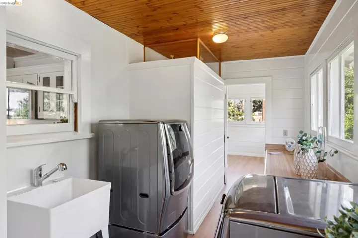 Bright utility space featuring a wood-finish plank ceiling, horizontal shiplap walls, and multiple windows