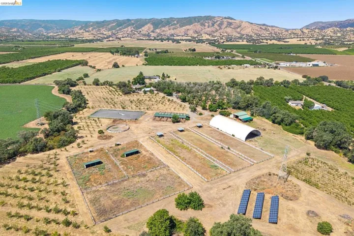 Expansive agricultural property featuring multiple fenced paddocks, a large covered structure, and an open riding arena