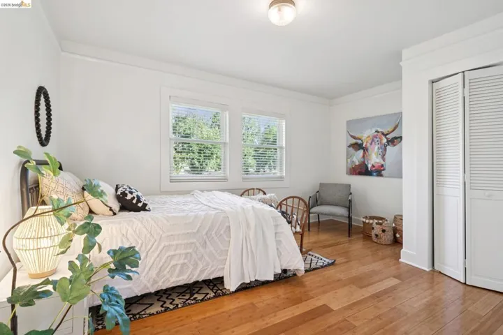 Bright room with wood-finish flooring, two windows with blinds, crown molding, and a flush-mount ceiling light
