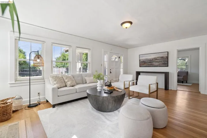 Light-filled room featuring wood-finish flooring, multiple windows with blinds, a white ceiling, and a white entry door with frosted glass panels