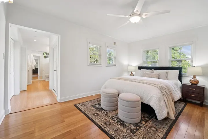 Bright bedroom featuring wood-finish flooring, white walls, and a ceiling fan with integrated lighting