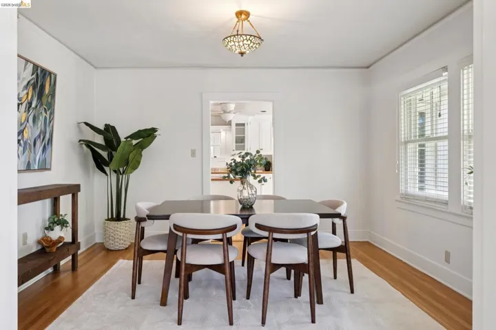 Dining area featuring hardwood flooring, white wall finishes, a decorative ceiling fixture, and natural light from multiple windows
