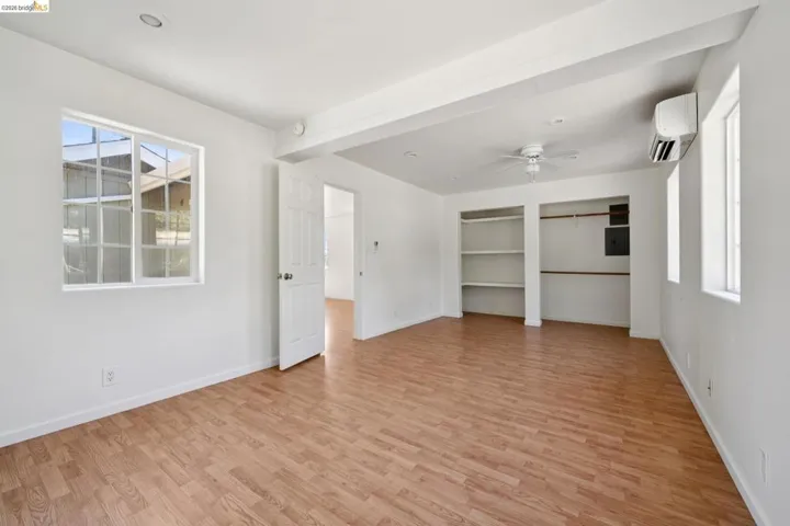 Spacious room featuring wood-finish flooring, white walls, and multiple windows for natural light