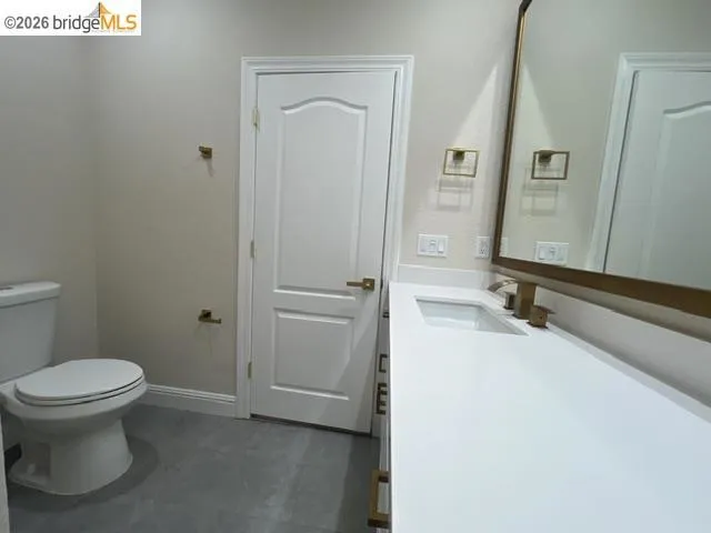 Bathroom featuring a white vanity with a rectangular undermount sink, white countertop, and gold-finish fixtures
