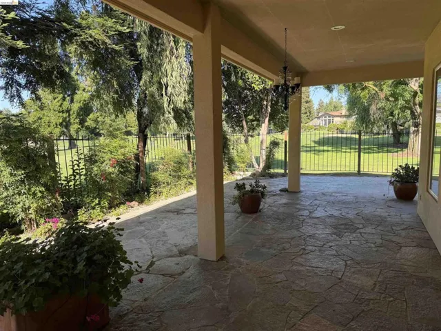 Covered patio featuring flagstone flooring, stucco columns, and an ornamental chandelier