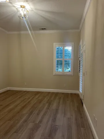 Gorgeous golf course view.  Spacious room featuring wood-finish flooring, crown molding, and plantation shutters