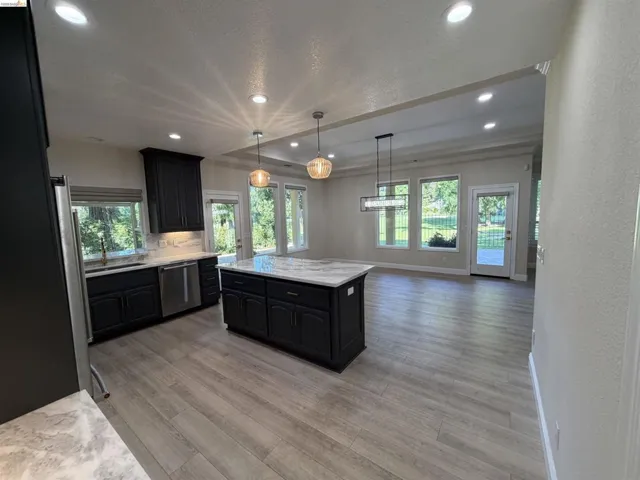 Open-concept kitchen and living area featuring wood-finish flooring, recessed lighting, and a kitchen island with a light-toned countertop