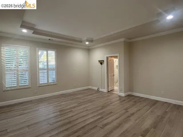 Spacious room featuring wood-finish flooring and crown molding