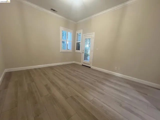 1st floor. Gorgeous gold course view. Spacious room featuring light wood-finish flooring, neutral wall paint, white crown molding, and white baseboards