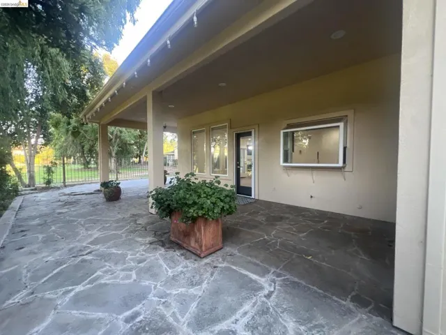 Expansive flagstone patio with a covered outdoor area, featuring multiple windows, a glass-paned door, and a pass-through window
