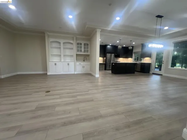 Spacious open-concept interior featuring light wood-finish flooring, recessed lighting, and a built-in wet bar with white cabinetry