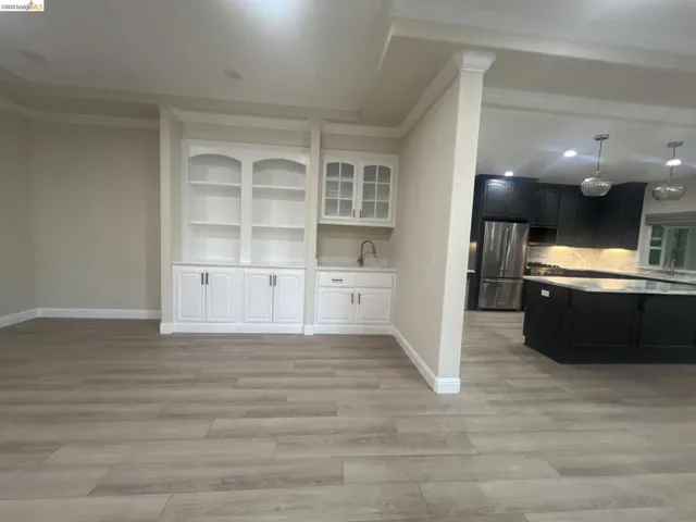 Built-in cabinetry with glass-front uppers and a wet bar featuring a single-basin sink