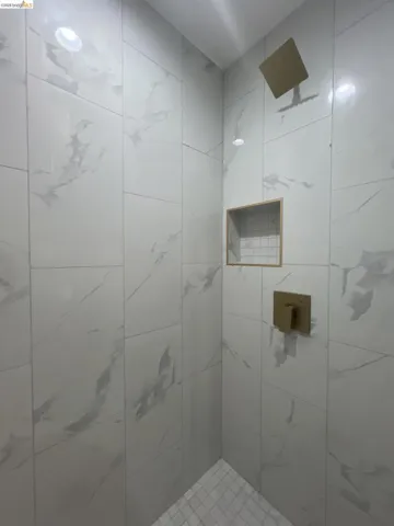 Upstairs Bathroom. Contemporary shower enclosure featuring large format with subtle veining, a built-in recessed niche with tile, square rain shower head and shower control