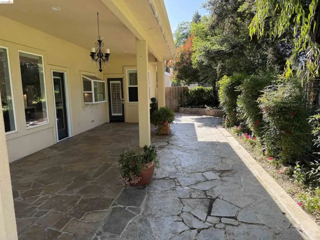 Expansive covered patio featuring flagstone paving, an ornate chandelier, and multiple egress points