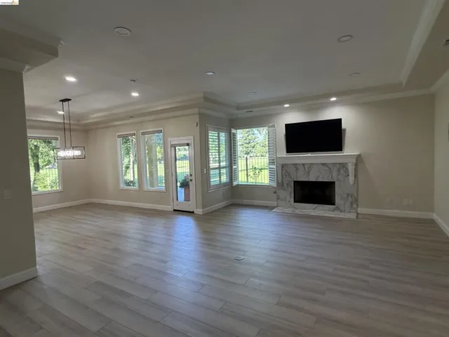 Gorgeous golf course views. Bright living space featuring wood-finish flooring, a white marble-clad fireplace, and multiple windows with plantation shutters