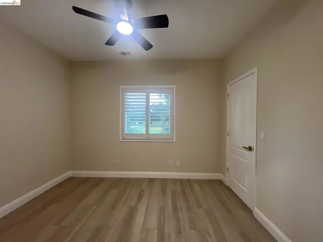 Gorgeous golf course view. Room featuring wood-finish flooring, white baseboards, and neutral wall paint