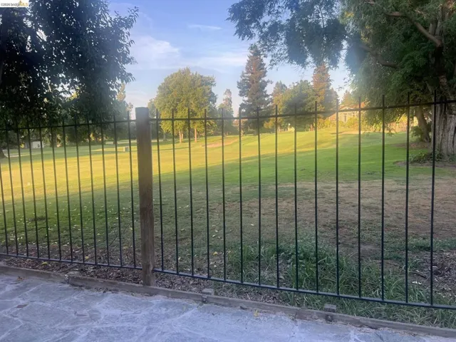 Gorgeous golf course view. Wrought iron fencing bordering a manicured green space with mature trees