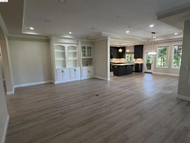 Open-concept living space with light wood-finish flooring, recessed lighting, and crown molding