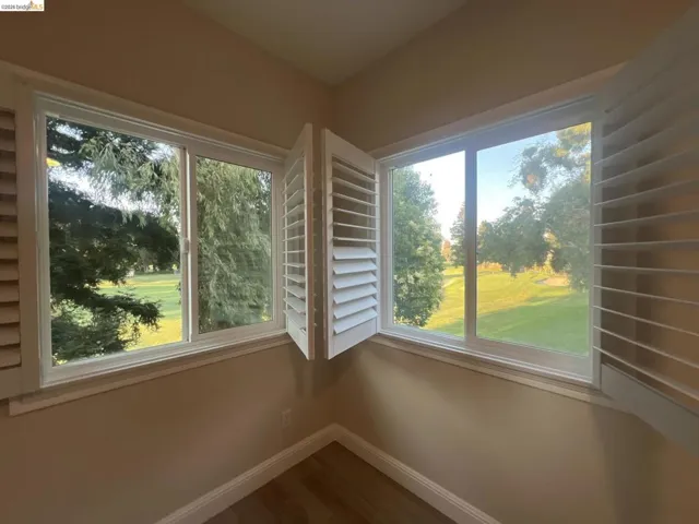 Gorgeous golf course view. Corner window configuration featuring white plantation shutters and views of mature trees and a grassy expanse