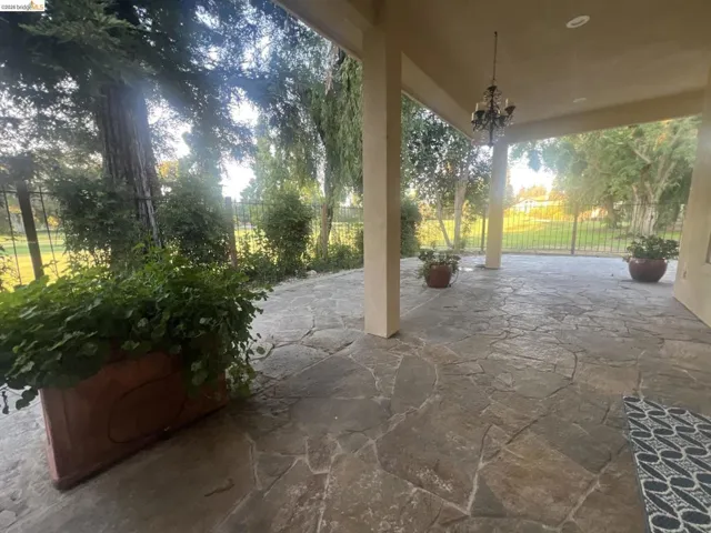 Covered patio featuring flagstone flooring, a decorative chandelier, recessed lighting, and a metal fence
