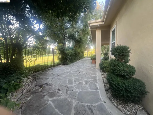Stone patio leading to a covered porch with stucco exterior