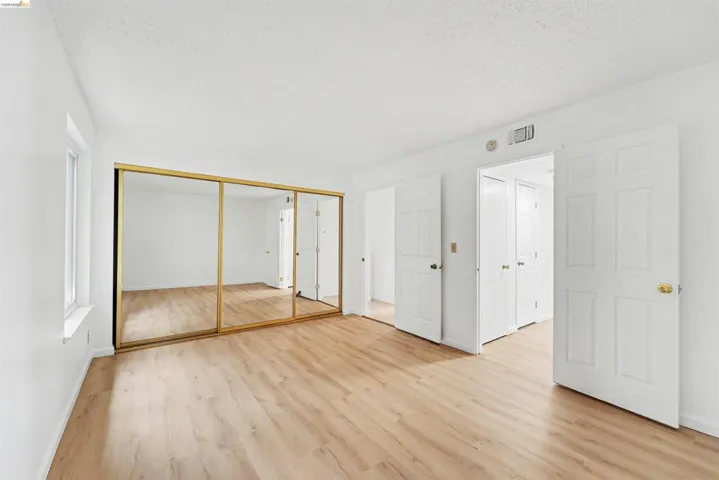 Room featuring wood-finish flooring, white walls, and a window with white trim