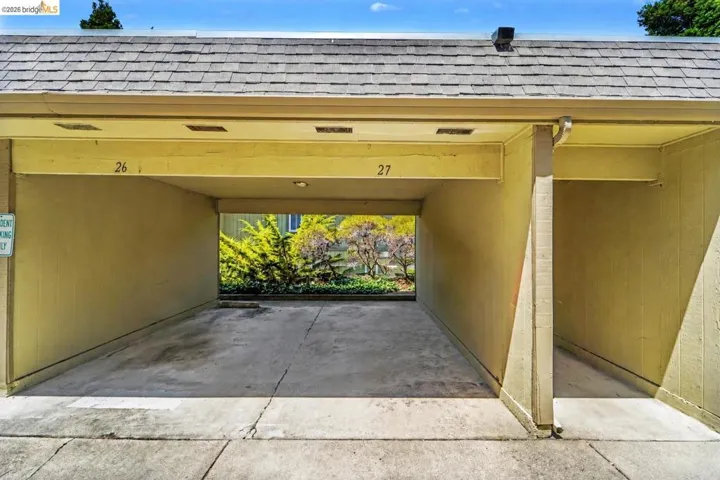 Covered parking space with concrete flooring and a shingle roof