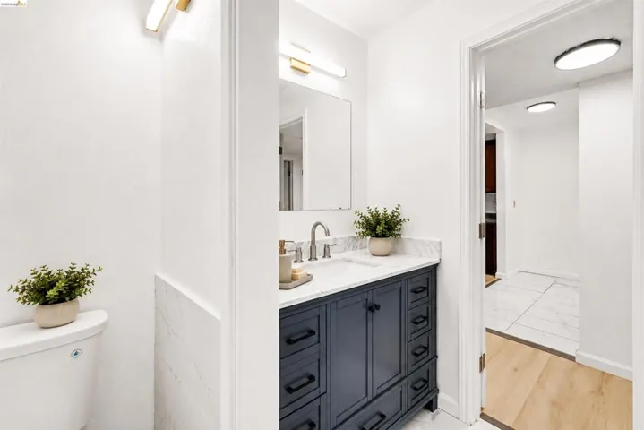 Bathroom vanity featuring a vessel sink, a marble-finish countertop, and a dark blue base with cabinet and drawer storage