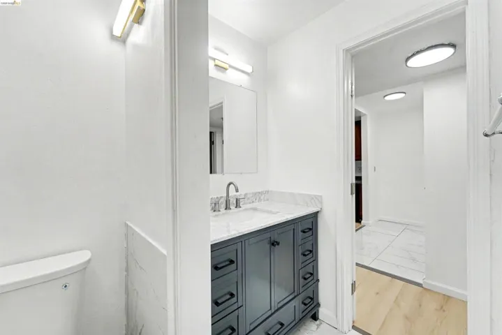 Bathroom featuring a dark wood-finish vanity with ample storage, a white countertop with integrated sink, and a brushed nickel faucet