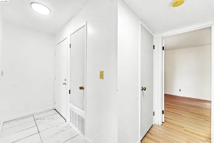 Entryway featuring white tile flooring, flush-mount ceiling lighting, and a white interior door with brass hardware