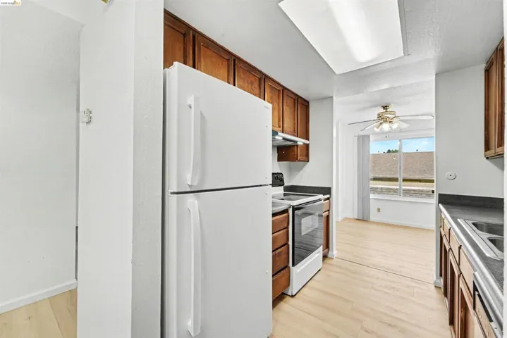 Kitchen featuring wood cabinetry, dark countertops, white refrigerator, and a white electric range