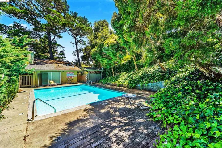 Outdoor swimming pool surrounded by a concrete deck and wood-finish patio