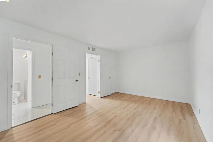 Bright room with light wood-finish flooring, white walls, and a white ceiling