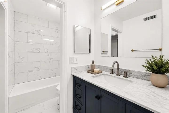 Bathroom featuring a dark blue vanity with black hardware, a white undermount sink, and a white marble-patterned countertop