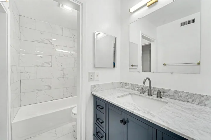Bathroom vanity featuring a quartz countertop with integrated sink and brushed nickel faucet