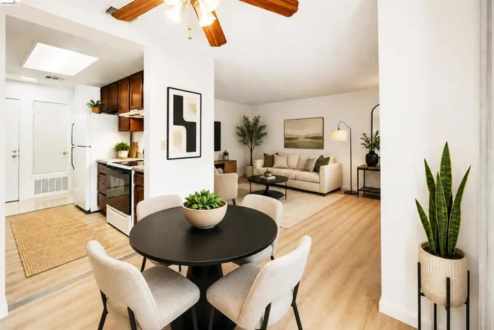 Combined living and dining space featuring wood-finish flooring, a ceiling fan with integrated lighting, and white painted walls