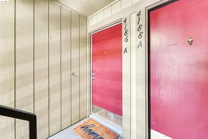 Entryway featuring a bright red door with a partial glass insert, contrasting against vertical wood-panel siding