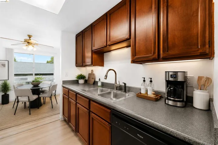 Kitchen featuring wood cabinetry, a dual basin stainless steel sink with a high-arc faucet, and dark countertops
